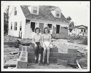 Wareham House Moving by hurricane. Mary Lou (left) and Kathleen Mather of Franklin, seated on the foundation. The house is behind them.