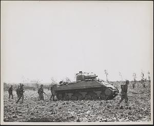 Advancing against the Japanese forces on Tinian island are teams of Marine Corps riflemen and their tanks