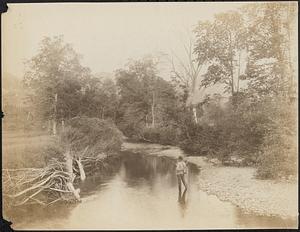 A man fishing in a shallow river