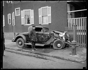 Policeman stands by a damaged car