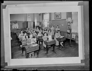 Children holding up their work at desks