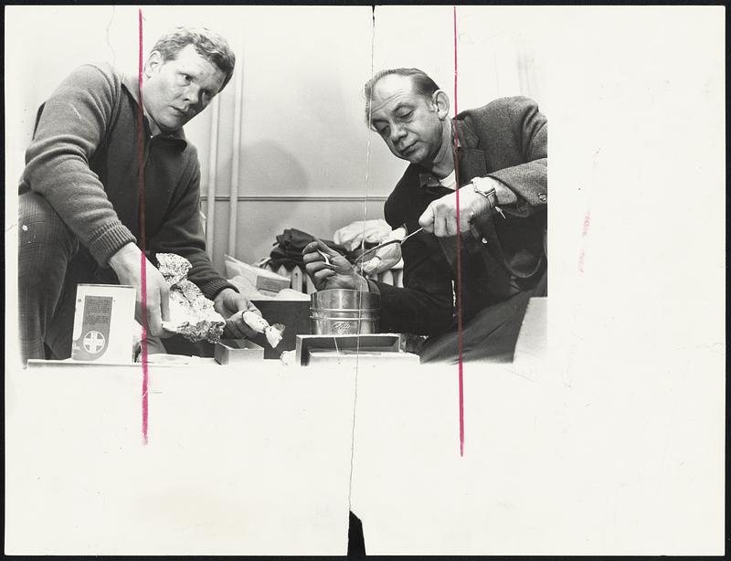 Narcotics Detectives Edward Simmons, left and Arthur Linsky inspect some of the equipment seized in last night's raid in Dorchester.