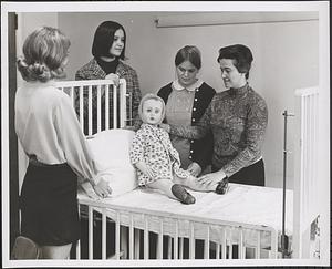Miss Helen D'Alelio, R.N., Pediatric Instructor at Saint Elizabeth's Hospital School of Nursing, gives, from the left, Peggy Earls, Janice O'Neill, and Christine Perry, lessons on proper care of "Suzie," the nursing school's "sick child"