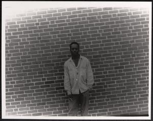 Young man posing against brick wall