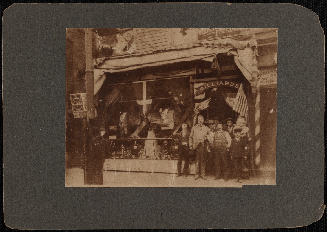 Men standing outside storefront to Cheap John's billiards and tobacco store