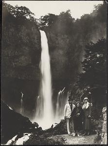 Three people standing in front of a waterfall