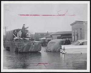 Anybody Want to be Rescued? - Special Officer Ralph Mele checks in the flooded Dunn road section of Revere where a score of residents were taken to safety yesterday by an amphibious DUKW. Many other residents elected to remain to wade about their living rooms hoping flood’s peak would soon pass.
