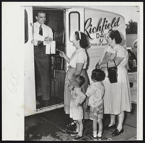 Doctor's Certificate or No Milk is the problem facing housewives in Washington, D.C. where a mile strike has made the precious fluid almost unobtainable. Here woman and children gather around an independent deliveryman in their quest for milk.