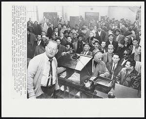 New York -- Awaiting Job Calls -- Unemployed seamen gather in front of the desk of Deck Dispatcher John Robinson in the national Maritime Union's hiring hall in New York, but the available jobs are few. The seamen are part of the 5,000 idled in the port of New York by the 27-day-old longshoremen's strike. Some of them are members of crews of foreign vessels stranded 4,000 miles from home.