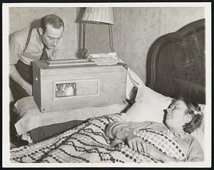 Father Builds Incubator for Baby Facing an Emergency When His wife Gave Birth to a Two and a Half Pound Daughter, March 7, Charles Bozurich, of Pittsburgh, Built an Incubator in Which He Has Kept the Infant Alive. He's Shown Here, March 12, Bending Over the Infant and Incubator, While His Wife, Still Confined to Bed, Looks on. Bozurich is an Unemployed Truck Driver.