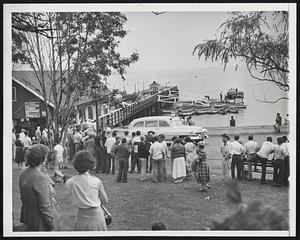 Storm Aftermath - Summer folks mingle with townspeople at a Salem Willows pier awaiting results of a search for bodies, after the violent storm which upset many boats in the harbor.