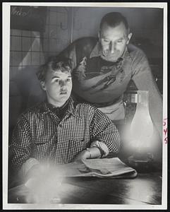 Storm Light Glows in Rogers pizza restaurant on Revere Boulevard, Revere, after power failed during the nor'easter which swept in from the sea. Mrs. Barbara Di Napoli of Somerville, and George Spellenberg of Revere, scan a paper by the improvised light.