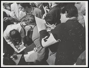 One Youth uses a friends back to sign draft resistance form, while others use table during draft resistance rally.