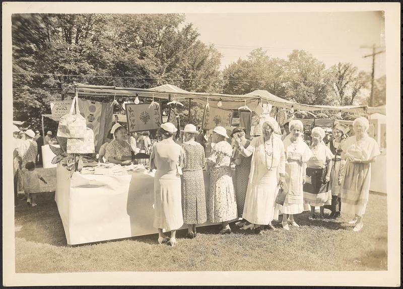 Booths at street fair, with women in costume