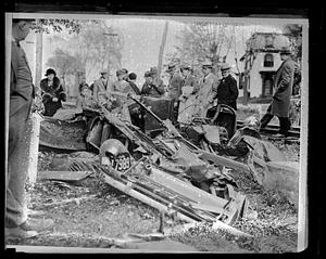People gathered around a completely wrecked car