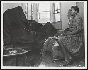 A Very Lucky Miss Ethel Hill, 374 Columbus Ave, Sits in Front Room of Her 3rd Floor Apt. Lighting Struck Her Top Floor Apt. Putting a Hole in the Roof and Also Knocking Plaster From Her Bedroom Wall. The Tarp Seen in Photo is Used to Protect Her Other Furniture From the Rain. Weather - Storms - Rain and Damage 8-5-52