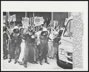 Burbank, Calif. – Police Hold Back Lockhead Strikers – Police restrain strikers of the International Association of Machinist as a truck entered the struck Lockheed Aircraft Corporation missile plant at Van Nuys, Calif., today. The walkout was generally peaceful, with only several minor incidents reported. The strike, over a contract dispute, began last midnight, but during the day President Kennedy took steps under the Taft-Hartley Act which could halt the walkout. The company has aerospace plants in several cities.