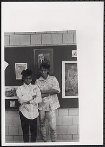 Nicole Nelson and another young woman standing in front of art work in a classroom or hallway