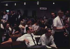 People sitting and standing near "Tennessee" sign in crowded room