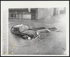 It Floats--Heavy rains flooded this downtown Providence street causing this small foreign car to float along before coming to rest on top of a submerged vehicle.
