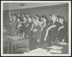 Pledging Allegiance To The Flag of their adopted land are these pupils at the Day School for Immigrants in a classroom at Brandeis Vocational High School. The school has old and young representatives of 29 nationalities.