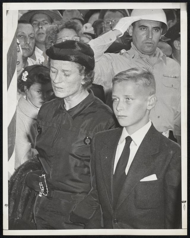 Grief Stricken, Mrs. Maurice J. Tobin, accompanied by her 15-year-old son, Maurice, Jr., entering Cathedral of the Holy Cross yesterday to attend a Requiem for her late husband who died Sunday at the age of 52.