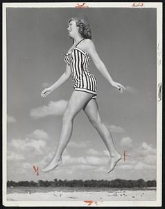 Dancer Sally Ardrey apparently disproves existence of gravity at Cypress Gardens as she is caught by camera in a very low orbit over sands of Florida tourist spot.
