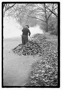 A man raking and burning leaves