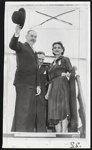 Hawaii Bound--Secretary of State Acheson waves a parting salute as, with Mrs. Acheson, he departs from the International Airport at San Francisco for the Pacific Mutual Security Conference in Hawaii. Between them in background is Phillip Jessup.