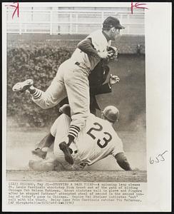 Stopping a Base Thief -- A spinning leap clears St. Louis Cardinals shortstop Dick Groat out of the path pf sliding Chicago Cub Nelson Mathews. Groat clutches ball in glove and fingers after he stopped Mathews' attempted steal of second in the second inning of today's game in Chicago. Umpire Mel Steiner indicates "out" call with his thumb. Relay came from Cardinals catcher Tim McCarver.