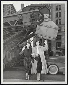 Hottest Mid-Winter Day On Record - Coat off and coat open, Evelyn Elsden and Louise Campbell walk under highly useless snow-leading equipment stored on a downtown Boston street as the temperature hit a record 72 degrees. This was the highest mark ever recorded in Boston for any of the winter months of December, January and February. The snow loaders haven't been used yet this season.