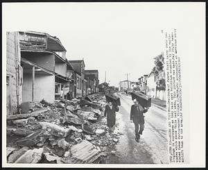 Ruins And Victims -- Residents of Puerto Montt carry their belongings in suitcases as they walk past buildings crumbled by the earthquakes which shook Chile last week. This picture was made, May 29, by Associated Press Photographer William J. Smith, who accompanied an American mercy airlift team to the area.