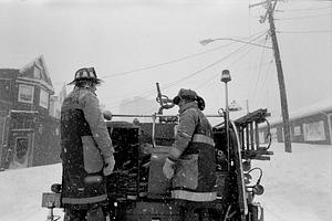 Chelsea firefighters Charlie Syzerbinski and Al Villani riding the back step of E3's 1956 Mack during the Blizzard of '78