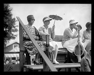 Helen Wills sitting in the stands holding an umbrella