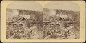 View from mountaintop, looking down railroad tracks to the piles of lumber below