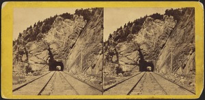 Looking down railroad tracks to tunnel through mountainside