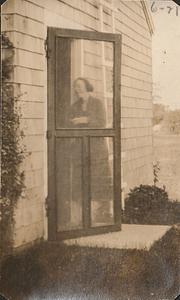 Woman at screen door, West Yarmouth, Mass.