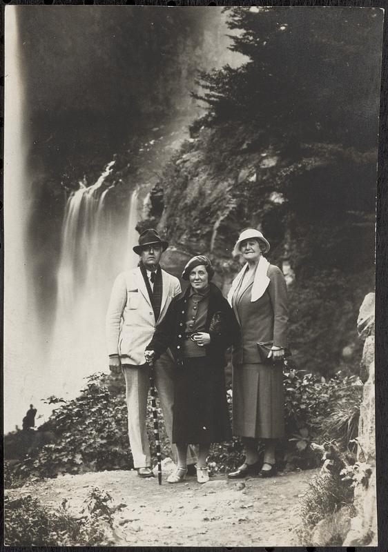 Three people standing in front of a waterfall