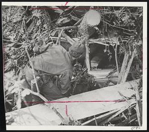 National Guardsman, one of thousands of rescue workers in grim search of flood victims, checks interior of car buried under debris carried by rushing water. More than 50 bodies were found yesterday and search will continue today.