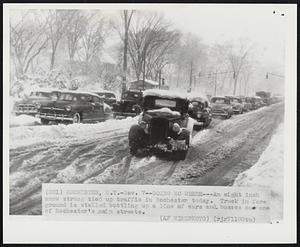 Rochester, N.Y. - Going No Where - An eight inch snow strong tied up traffic in Rochester today. Truck in fore ground is stalled bottling up a line of cars and busses on one of Rochester's main streets.