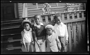 Four boys stand in front of fence