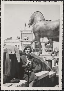 Woman sitting in front of a horse statue