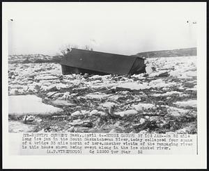 House Caught by Ice Jam--An 82 mile long ice jam in the South Saskatchewan River, today collapsed four spans of a bridge 35 mile north of here. Another victim of the rampaging river is this house shown being swept along in the ice choked river.