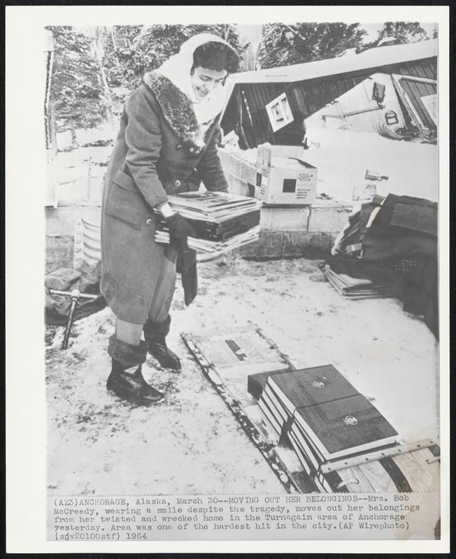 Moving Out Her Belongings -- Mrs. Bob McGreedy, wearing a smile despite the tragedy, moves out her belongings from her twisted and wrecked home in the Turnagain area of Anchorage yesterday.