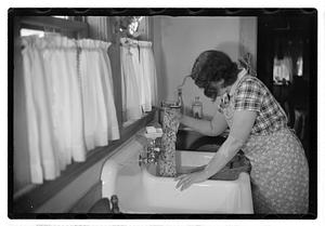 A woman doing laundry at a sink with a washboard