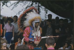 Man wearing feathered headdress conducting a band