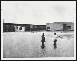 Midway shopping center, at right, off Hancock St. + warehouse in rear, frame flooded parking lot with car submerged to seat-tops.