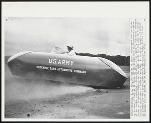Riding on Air-- A box-shaped machine kicks up a cloud of dust as it rises off the ground on a self-produced cushion of air during yesterday's demonstration at the James V. Forrestal Research Center at Princeton University. The unit, built for the Army by National Research Associates of College Park, Md., is reported capable of moving up a seven percent grade. Operated yesterday by Ralph Smith, it rose 15 inches off the ground.