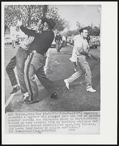 Restrained- Sheriff's deputies restrain a striker who plunged into the car of strikebreaker leaving the jalousies plant in Dayton. Action boiled up near closing time as striking employes and sympathizers heaved paint-filled eggs, coke bottles, and heavy lead balls at police and "scabs.".