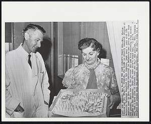 Even the Cake Doesn't Tempt Her--Mrs. Elaine Johnson and Dr. Ernst J. Drenick, who heads an obesity research program at Wadsworth Veterans Hospital in Los Angeles, look over a cake with 100 candles sent to Mrs. Johnson yesterday to celebrate her losing more than 100 pounds. She's one of the persons who has been starving away excess weight on the program. Even the cake didn't tempt her. "I don't eat, but I have lots of friends here who do," she quipped. Mrs. Johnson weighed 315 pounds when she entered the hospital. Now she's down to a [illegible]